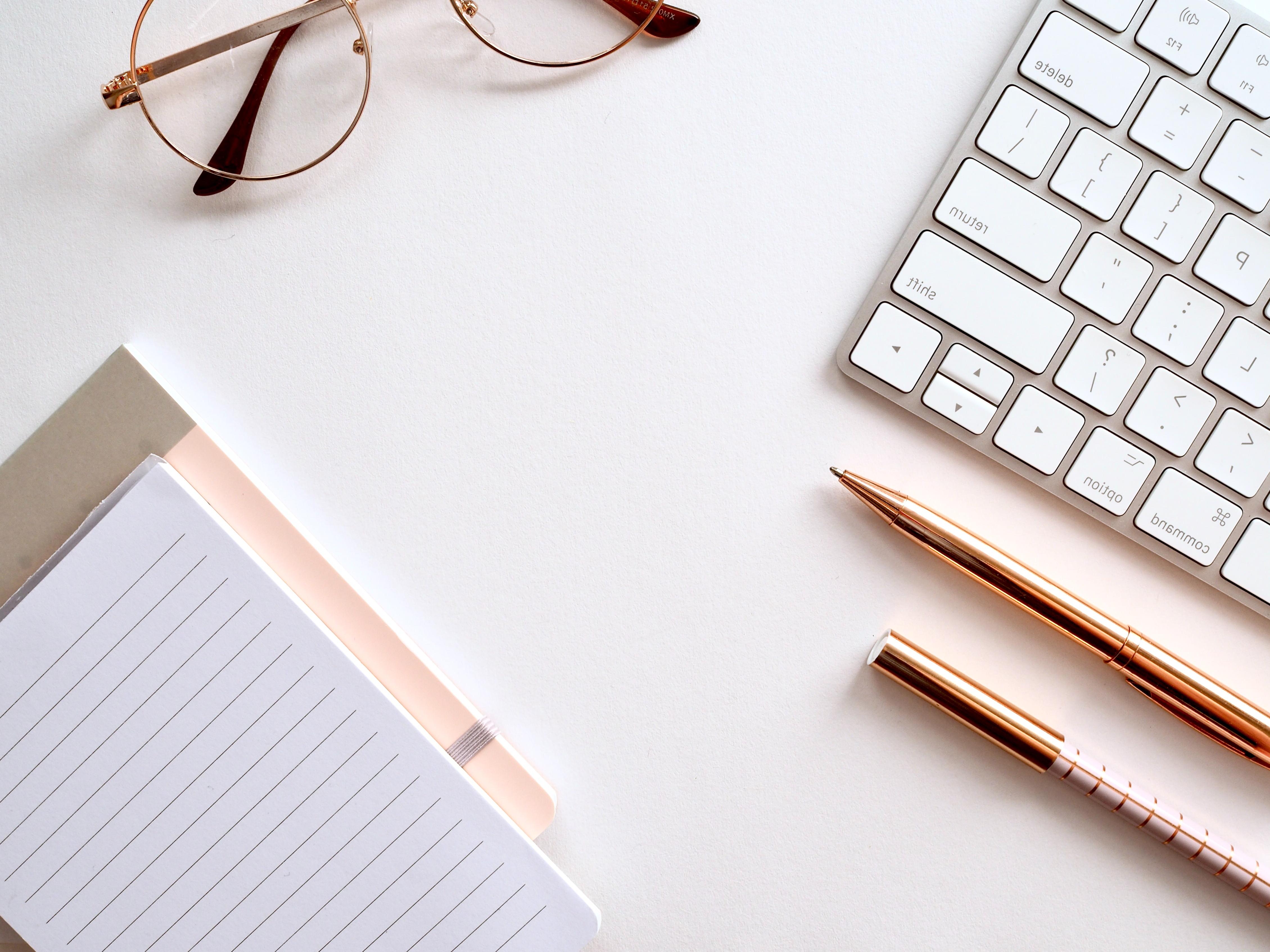 white background notebook, pencil, glasses, phone, and computer